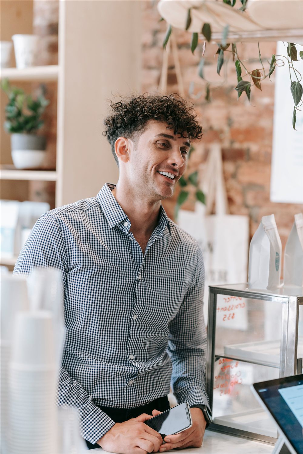 A small business owner smiling behind the counter of their shop